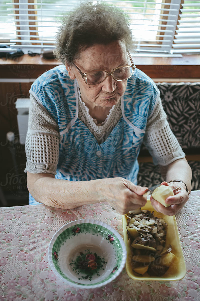 Old woman peeling potato