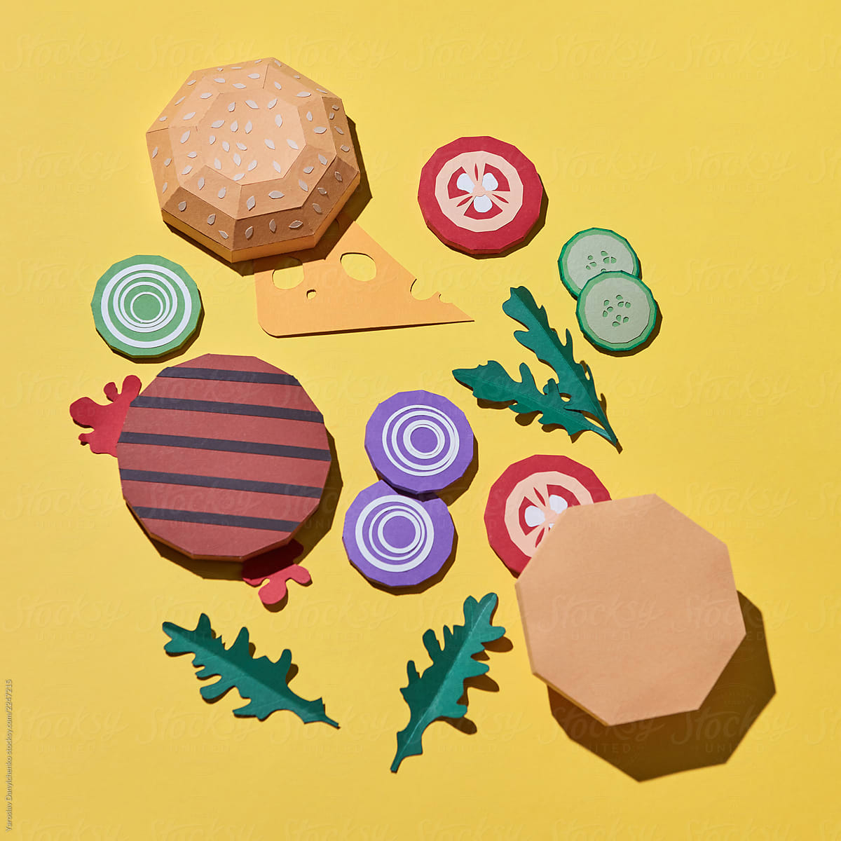 Paper craft set of ingredients from buns, cheese, vegetables and hamburger patties on a yellow background with copy space. Flat lay