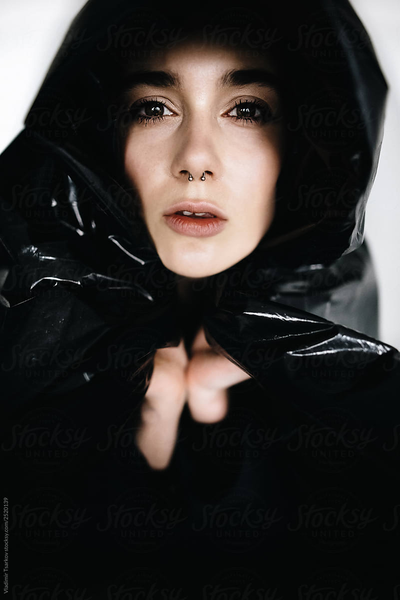 Fashion portrait of woman with earring in her nose in black plastic wrap