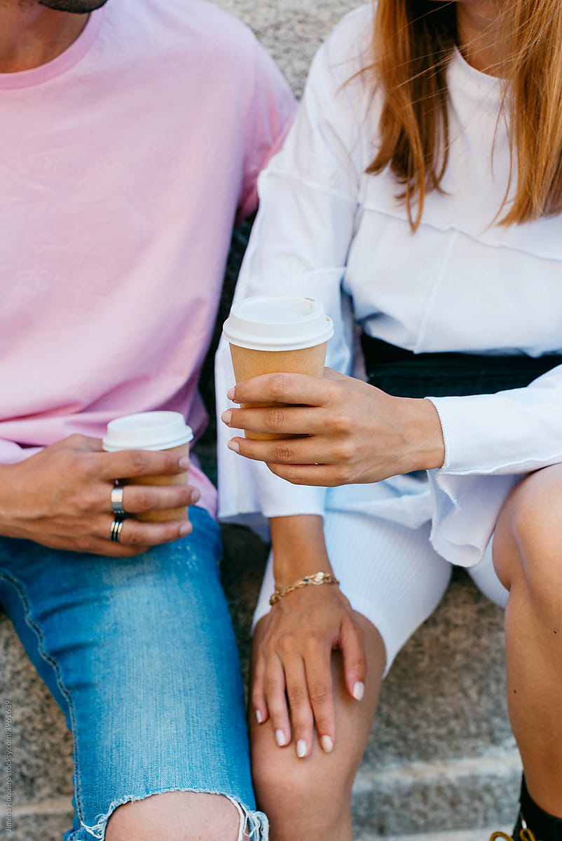Detail of young couple\'s hands holding coffee