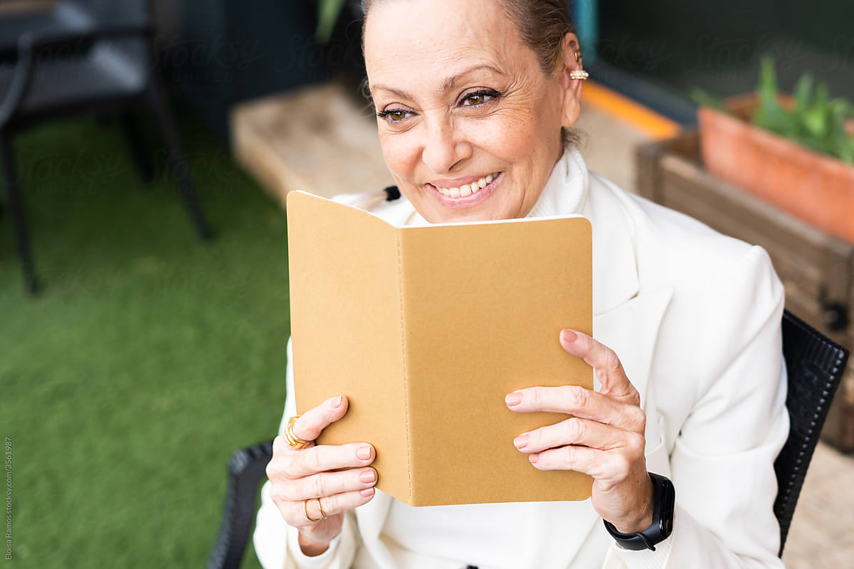 Senior woman smiling writing ideas in her notebook