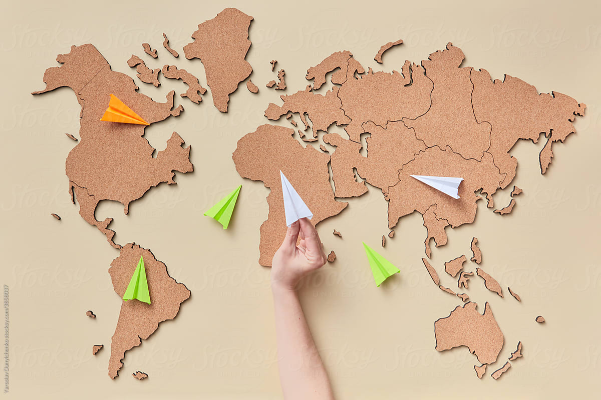 Woman holding paper plane above map