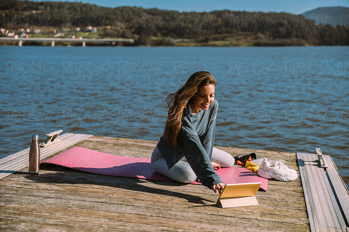 Woman in sportswear using tablet on pier