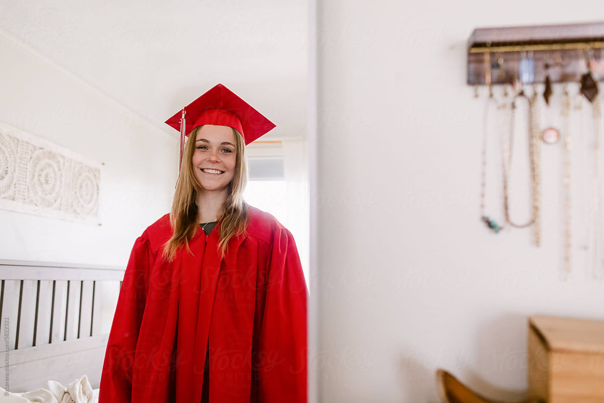 High school senior on red gown at home