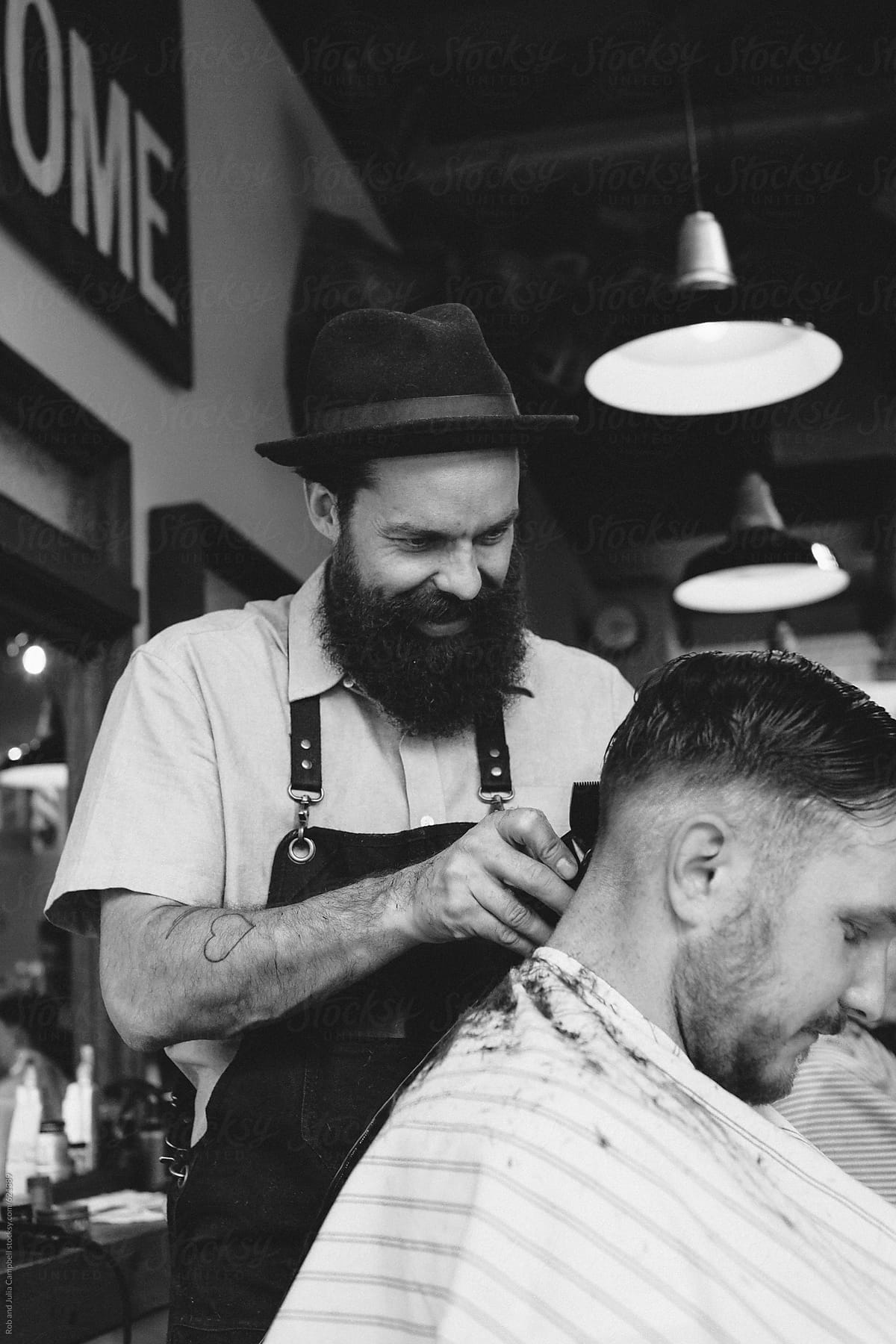 Stylish modern barber enjoying giving man a classic haircut