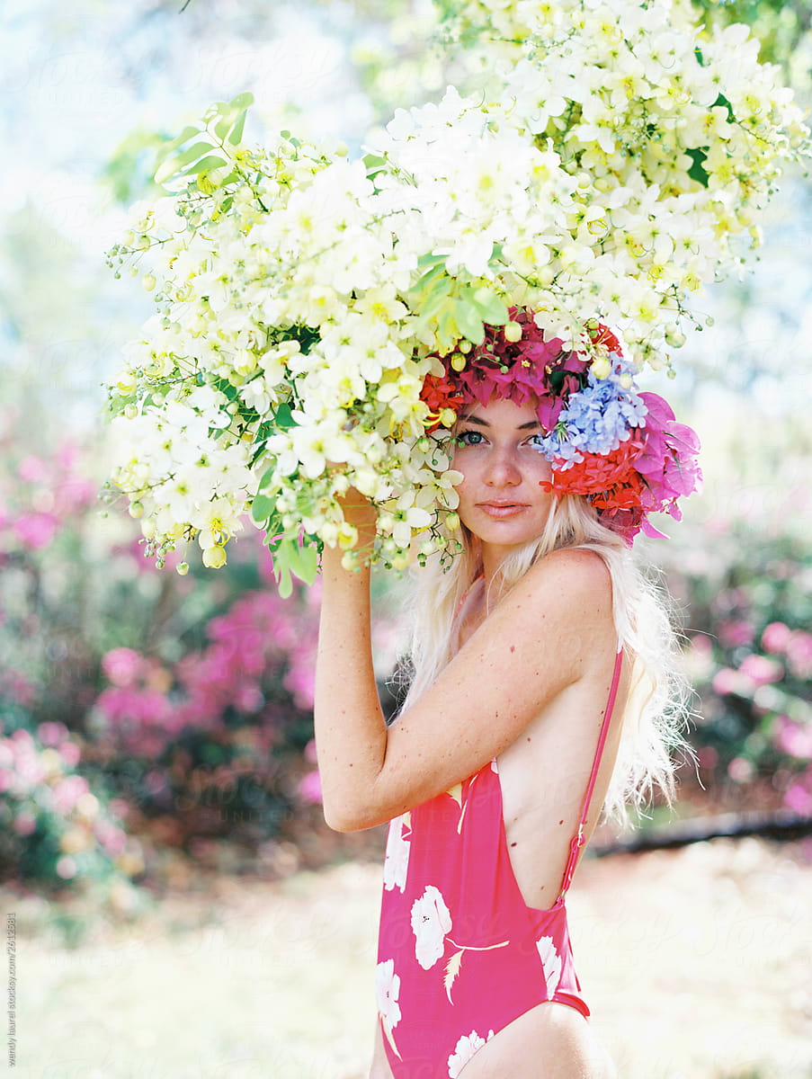 Blonde woman with floral crown and palm trees and flowers being happy and joyful with rainbow stripes