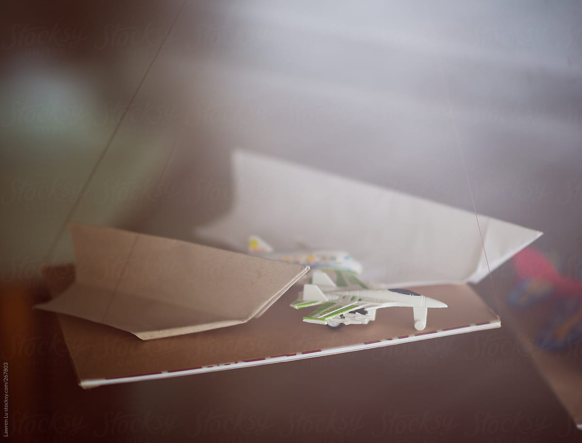 A small model plane and two big paper planes on the table
