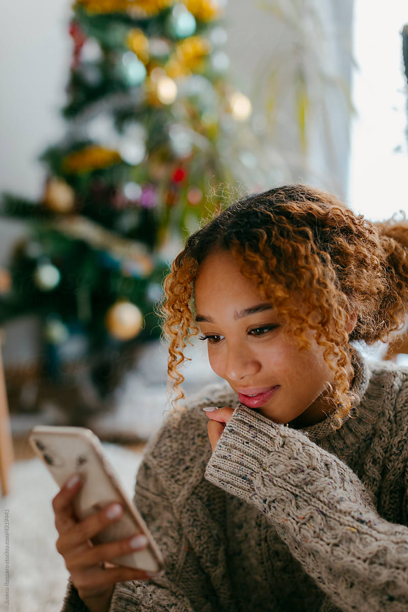 Girl smiling looking at her smartphone in Christmas