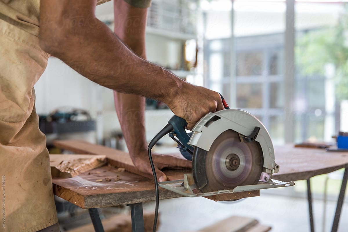 Carpenter using circular saw in his workshop