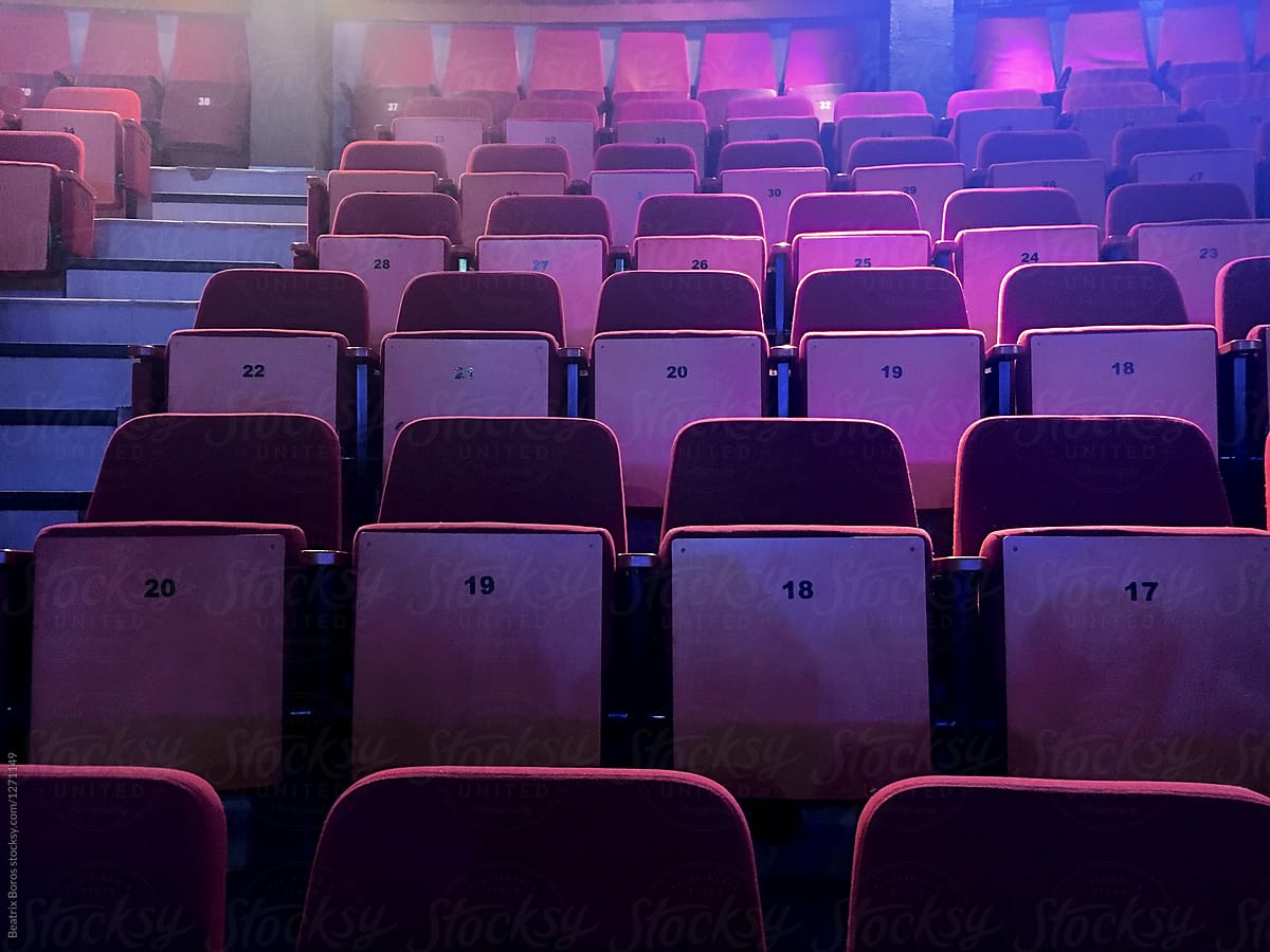 Empty row of seats in purple light in a theater