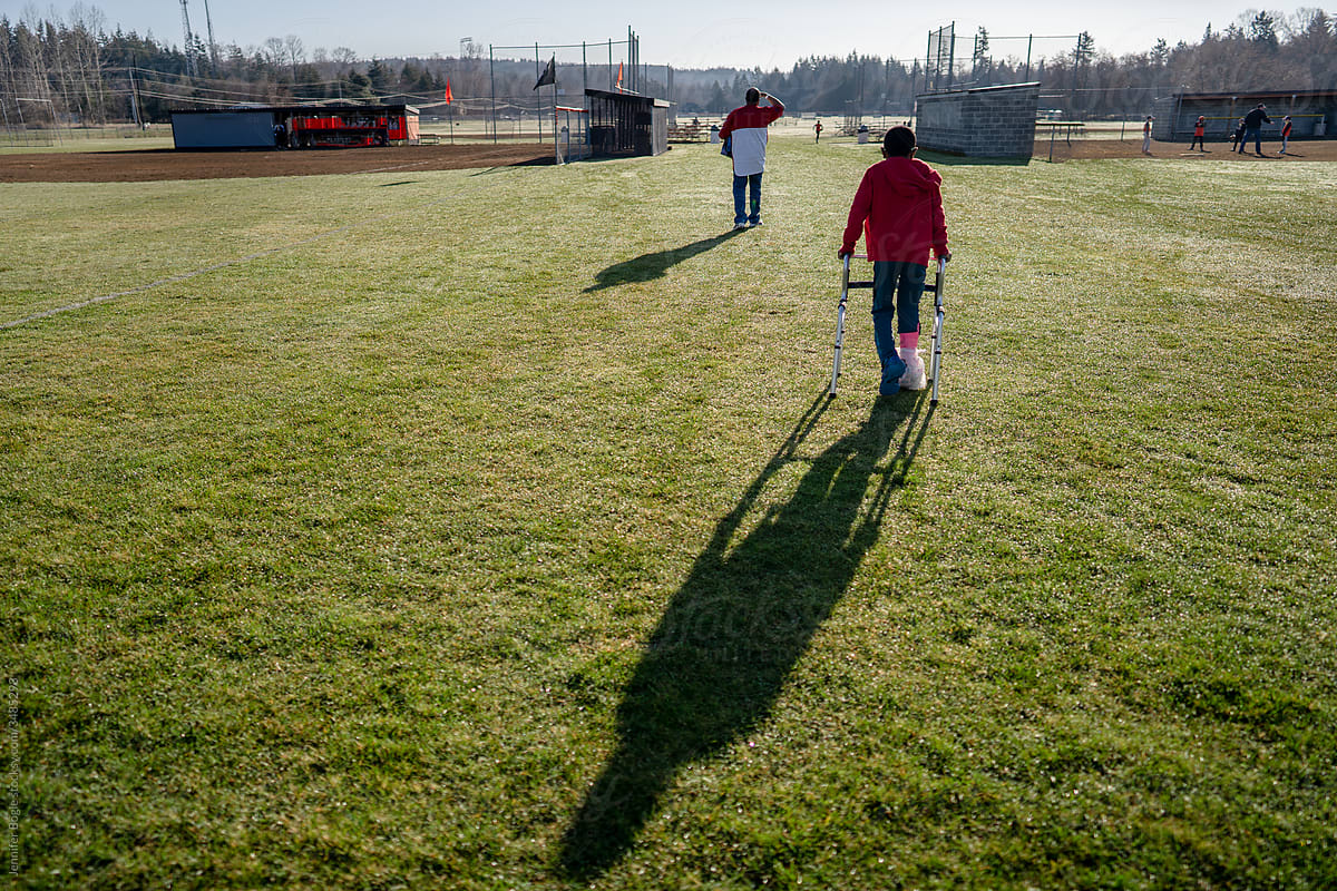 Boy on walker walks towards baseball field
