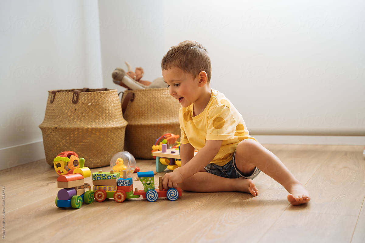 Happy cute child sitting on floor and playing with toys