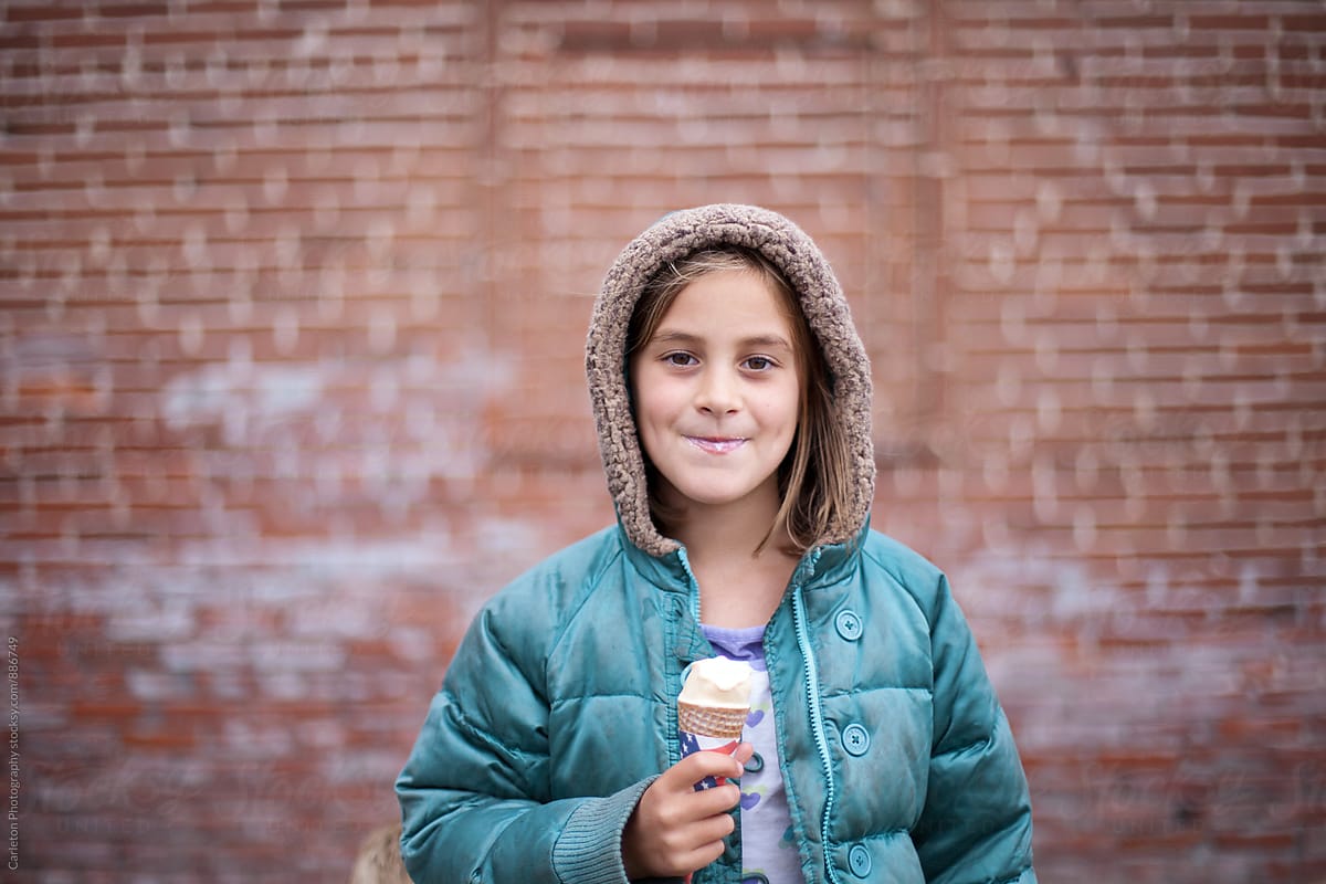 Girl enjoys ice cream in front of bricks
