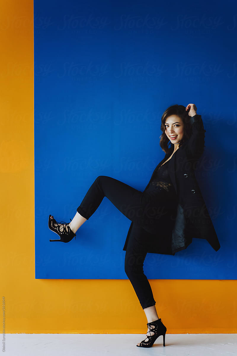 Full-length portrait of woman with perfect hair over blue and yellow background
