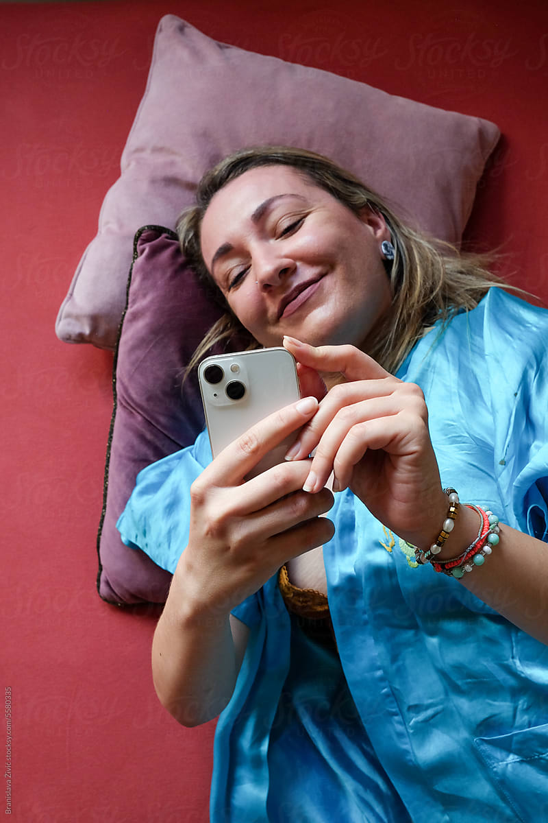 Woman lying in bed and taking photo with mobile camera