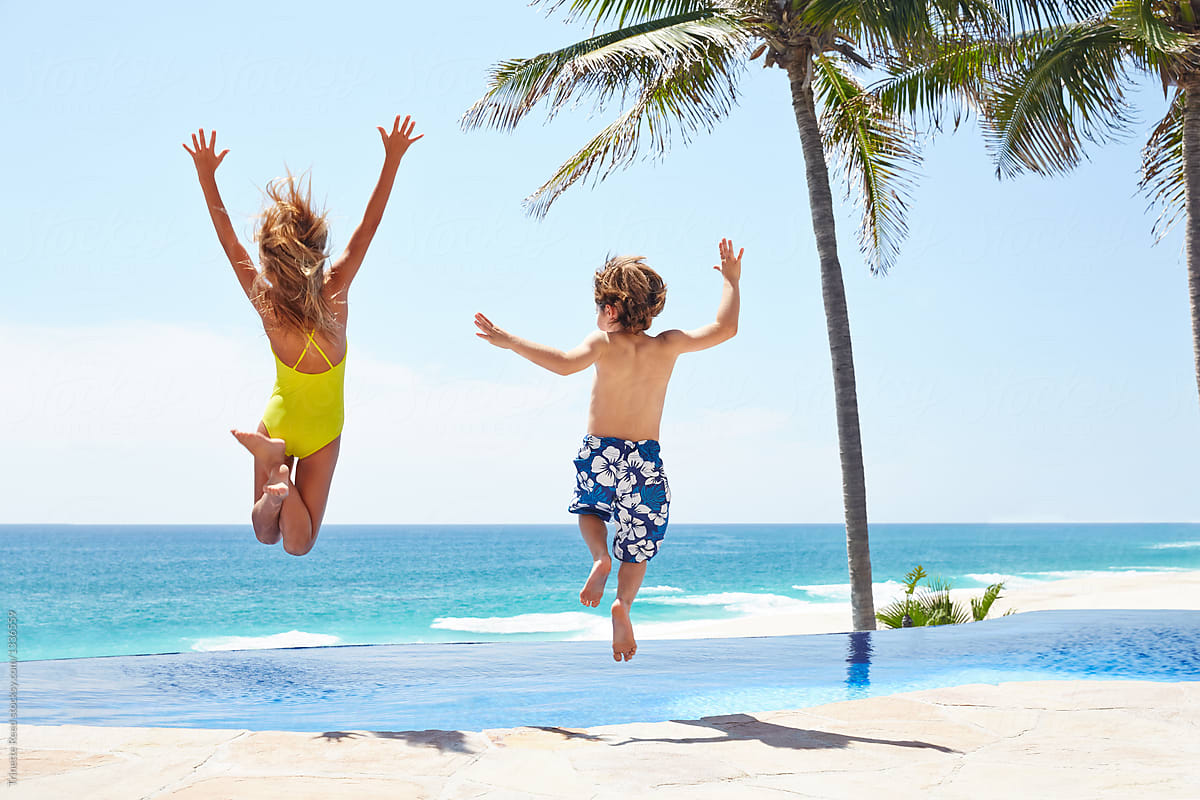 Kids running and jumping into a pool at luxury resort