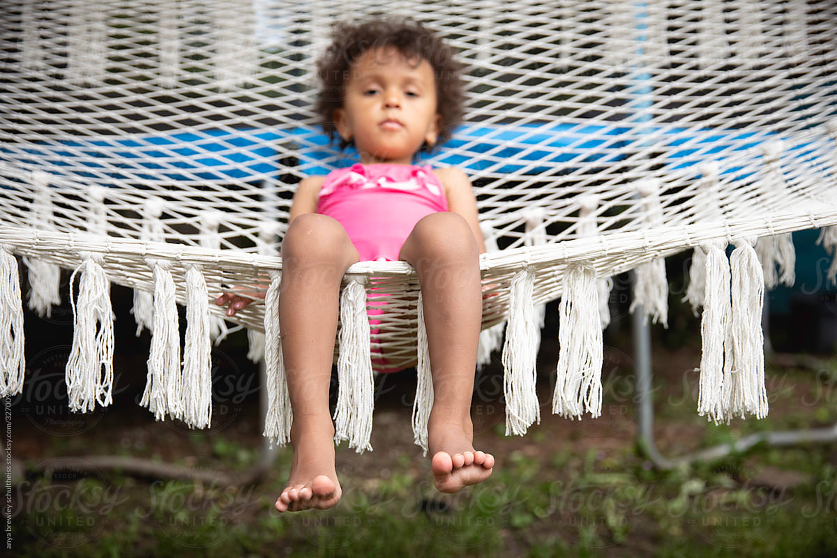 Toddler child lounging in a white cotton yarn hammock