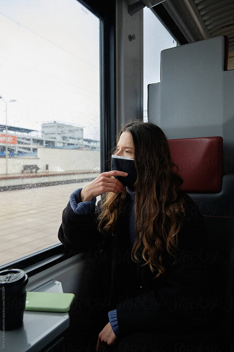 a lonely girl on a train in an empty carriage sits near a window with coffee next to on a shelf