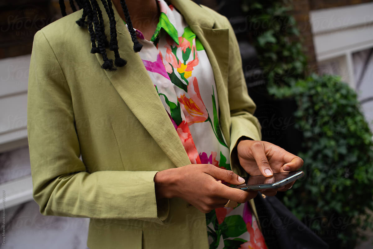 Black woman holding phone in her hands and a weekender bag