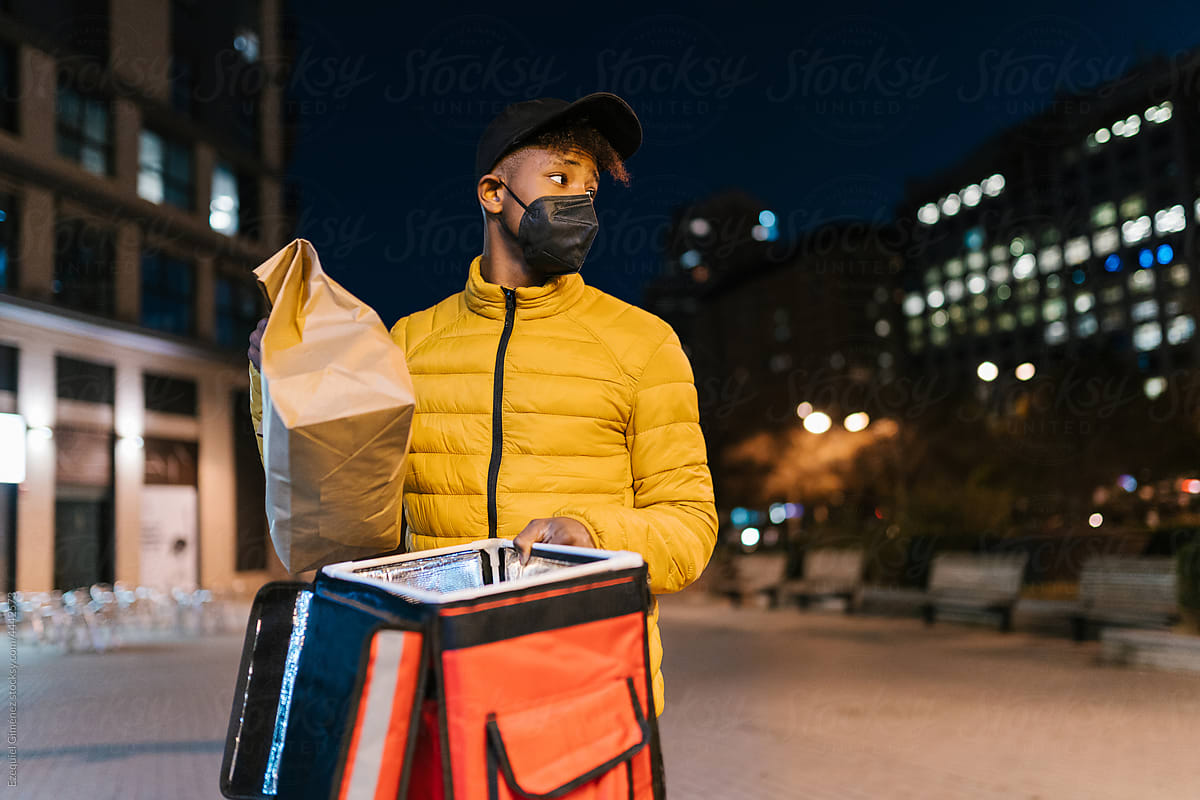Black courier with food order for delivery at night