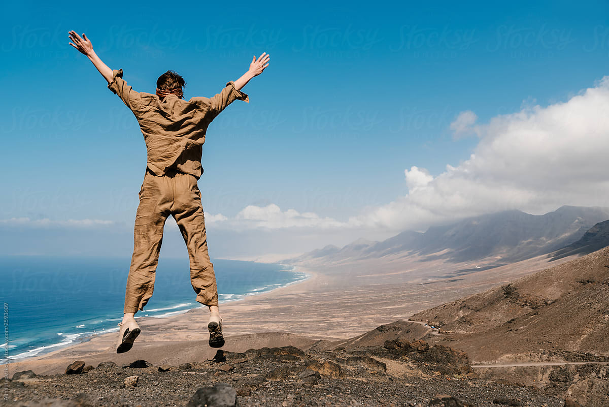 Girl jumping and rising up by hands on top of mountain