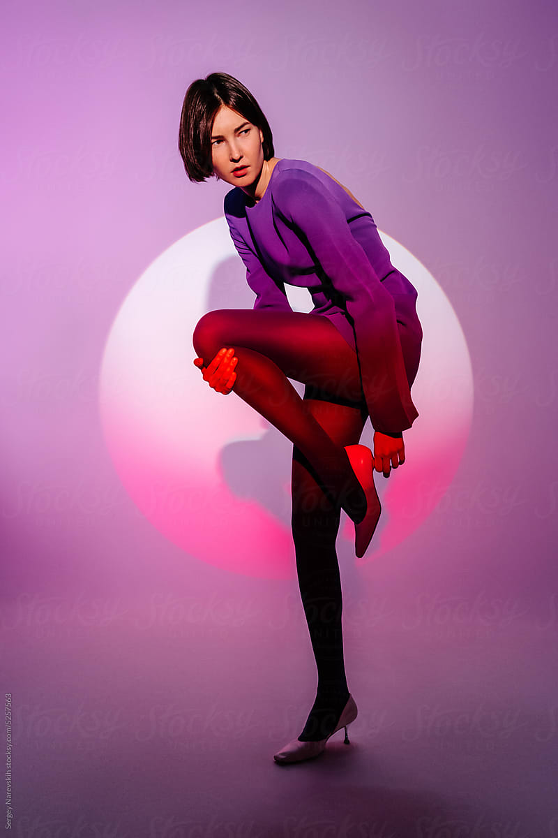 Model in purple mini dress posing in studio