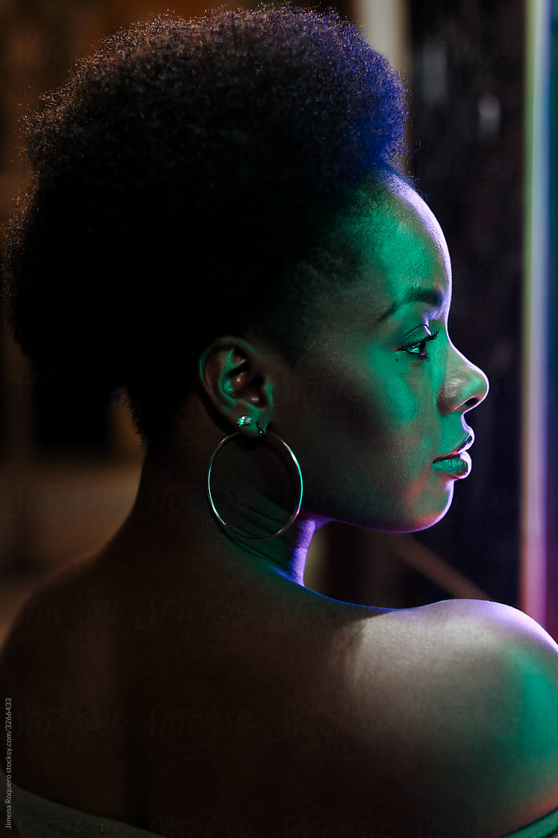 Profile portrait of Woman with afro hair outdoors in the city in a summer night.