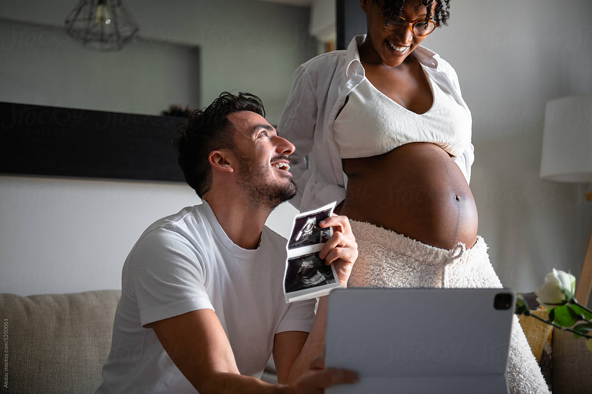 Happy pregnant couple showing ultrasound result on videocall