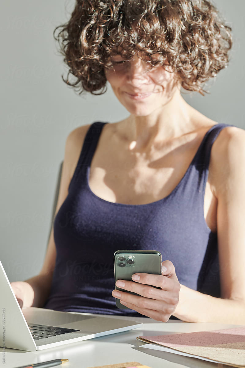 Cheerful girl with smartphone in office