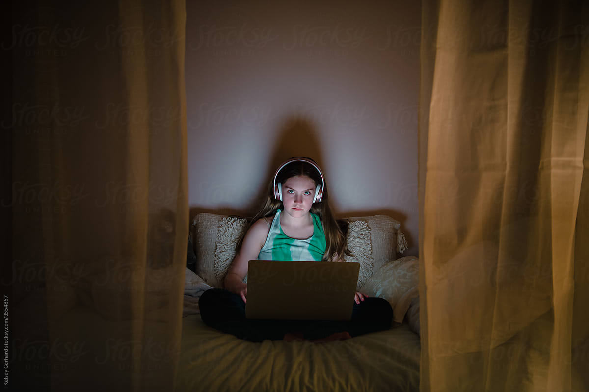 a child on a bed with a laptop and headphones.