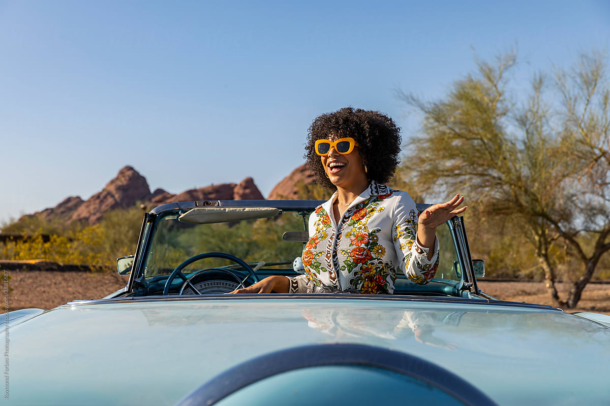 Elated young black girl on holiday with vintage car