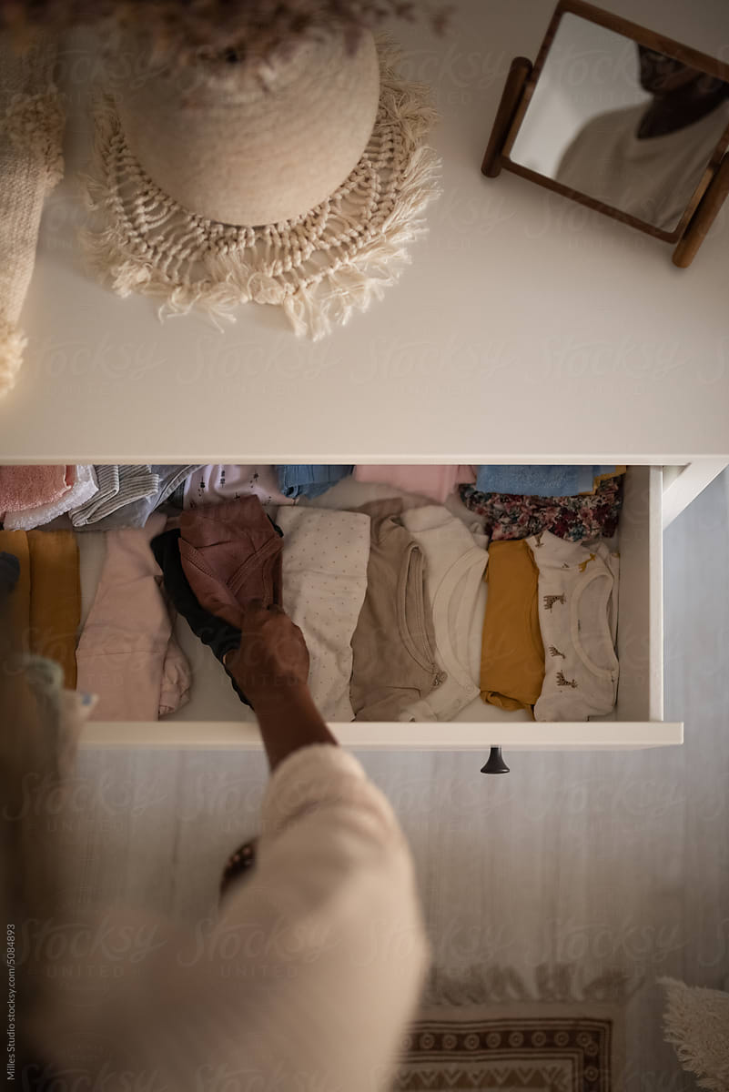 Crop woman arranging clothes in dresser