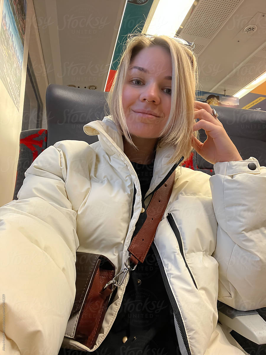 A young woman in stylish clothes is sitting in a chair on the train