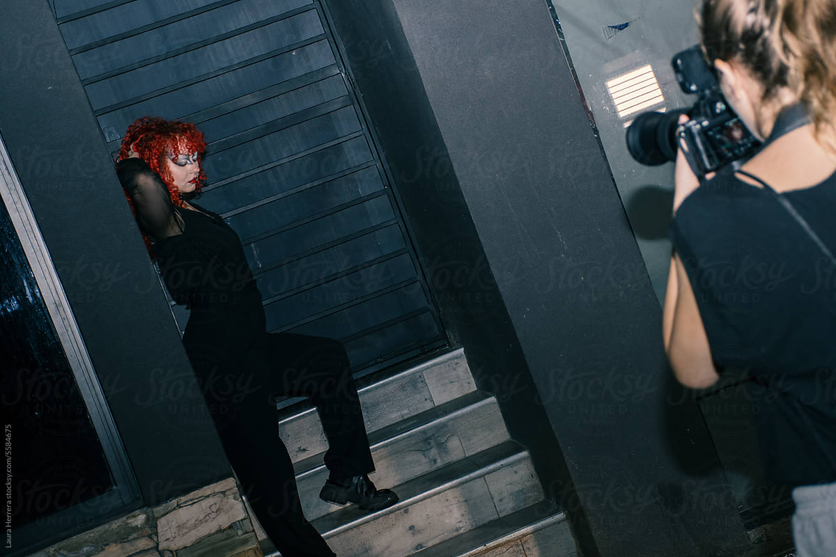 Gothic curly redhead poses on stairs while is recorded