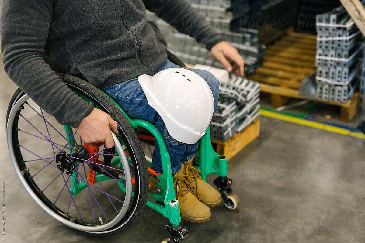 Man In A Wheelchair Holding A Helmet On His Knee