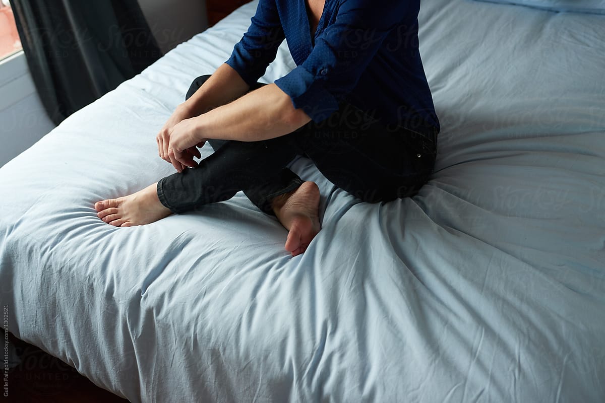 Unrecognizable woman in blue blouse on bed.