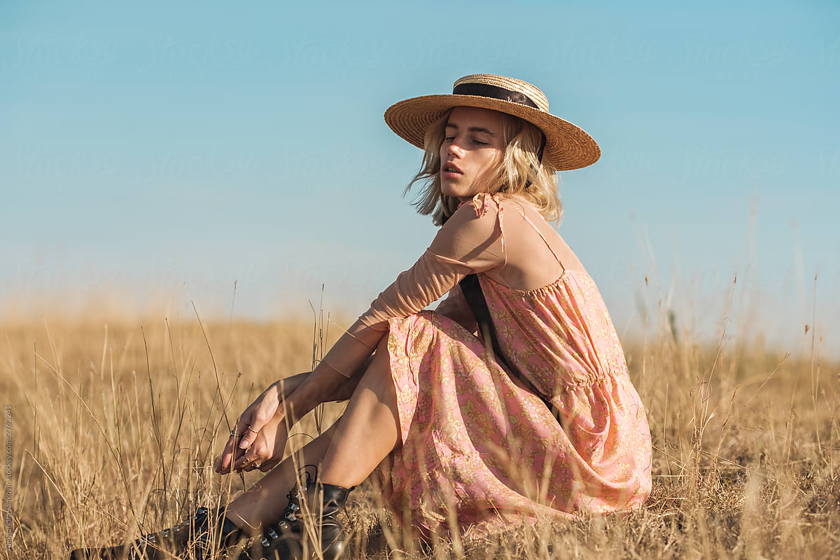 Sensual Blond Woman Wearing Silk Dress And Straw Sun Hat Outdoors