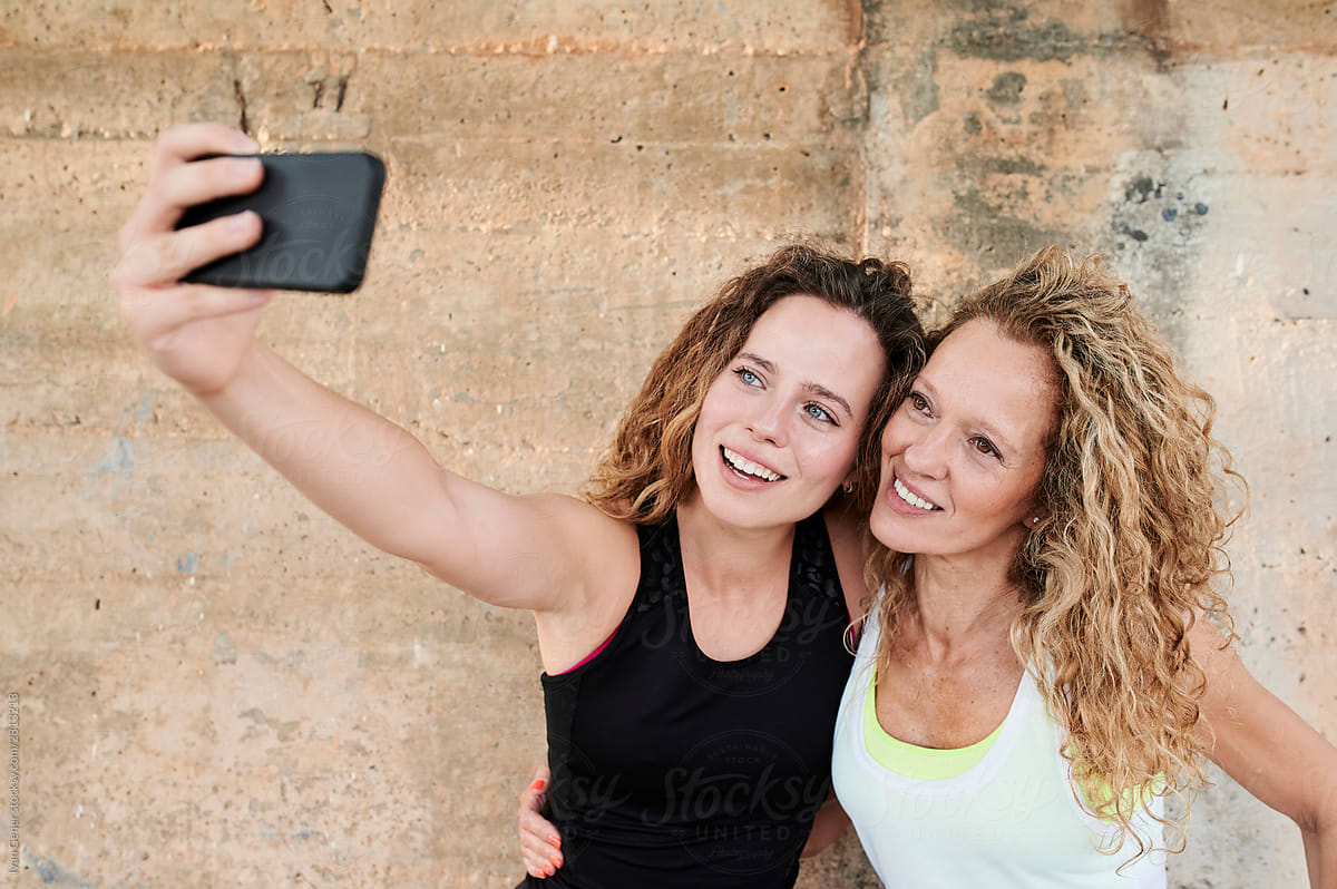 Sporty mom and daughter taking selfies