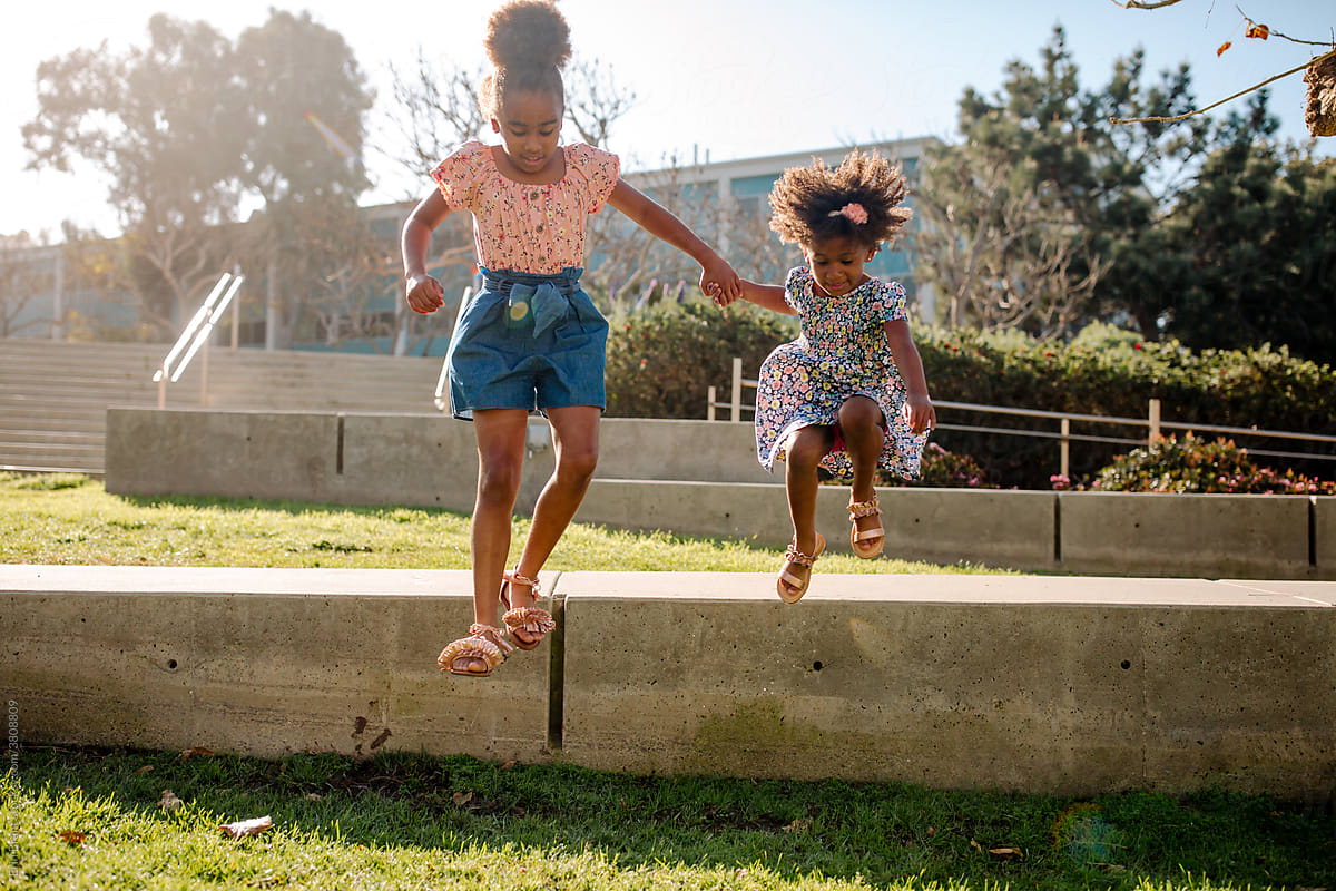 Young Black sisters leaping from ledge