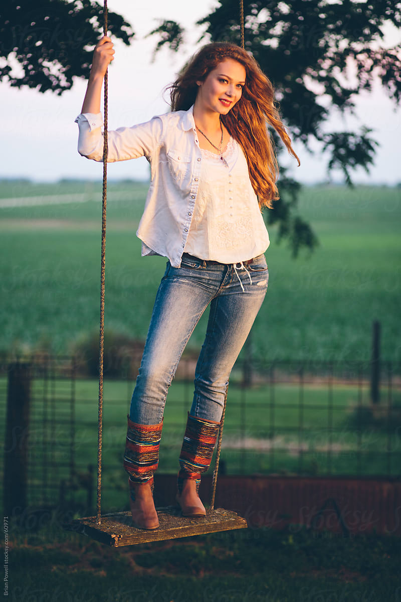 young woman standing on wooden swing