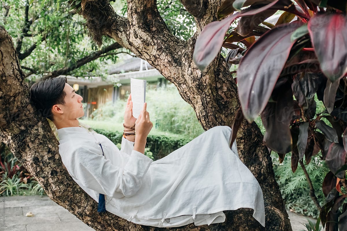 Asian man reading book in zen style traditional Chinese clothing