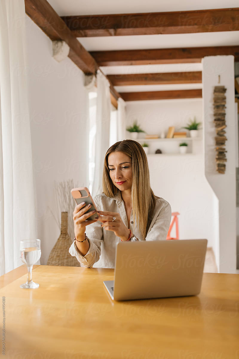 Happy businesswoman using smartphone at home
