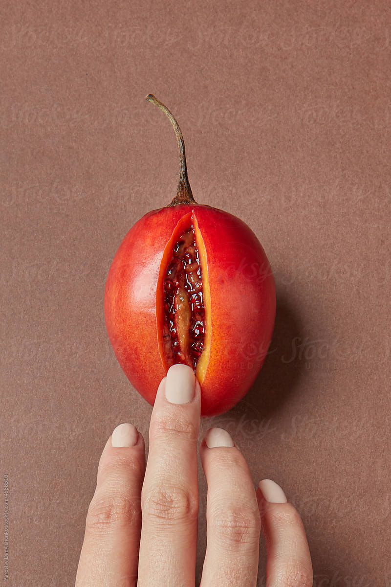 Woman\'s finger touching ripe tamarillo fruit