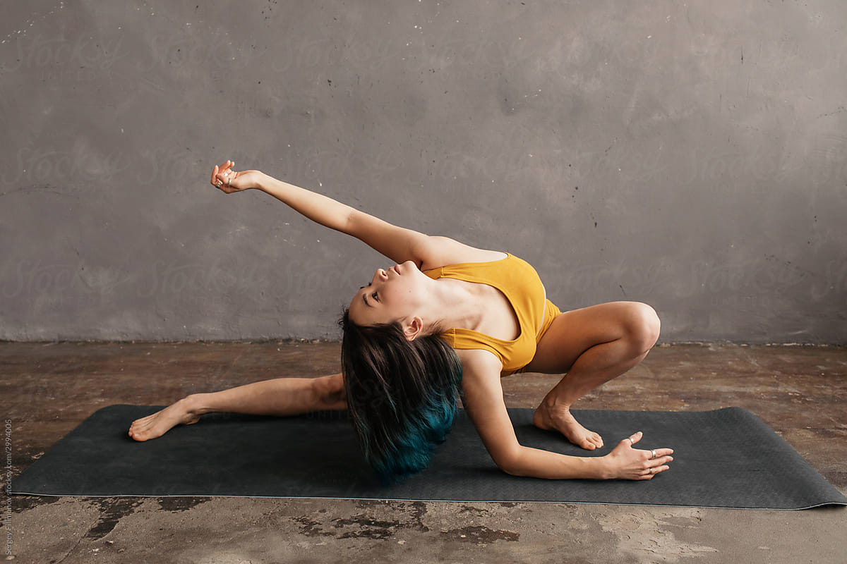 Slim ethnic woman doing yoga near shabby wall