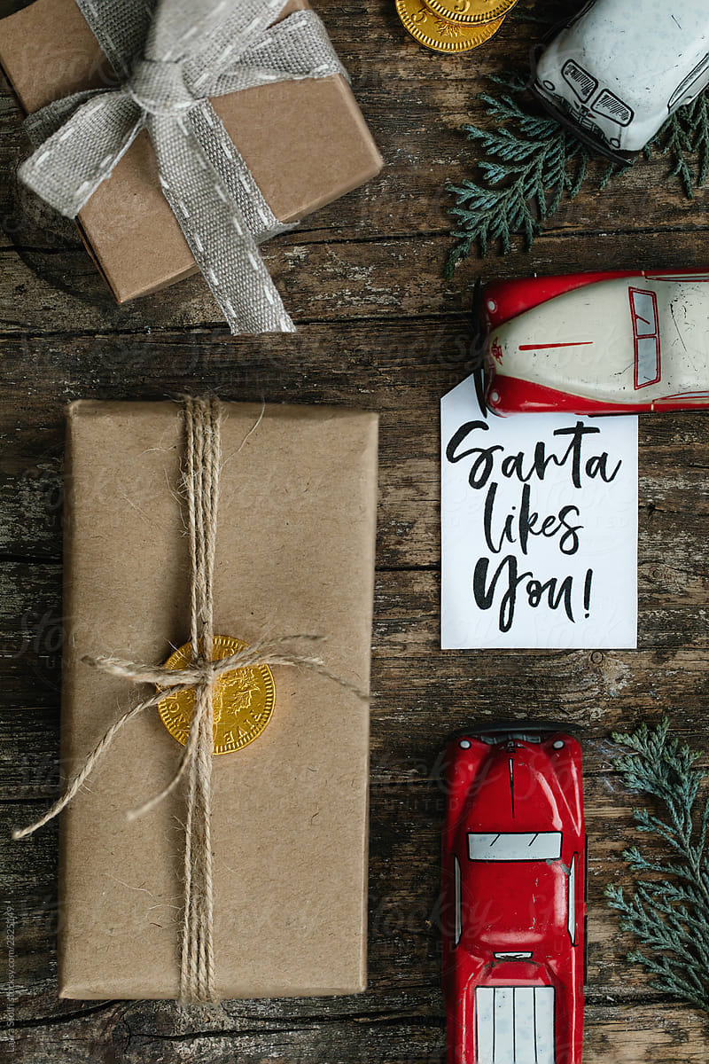 Presents wrapped in kraft paper, three vintage metal toy cars and a tag saying Santa likes you.