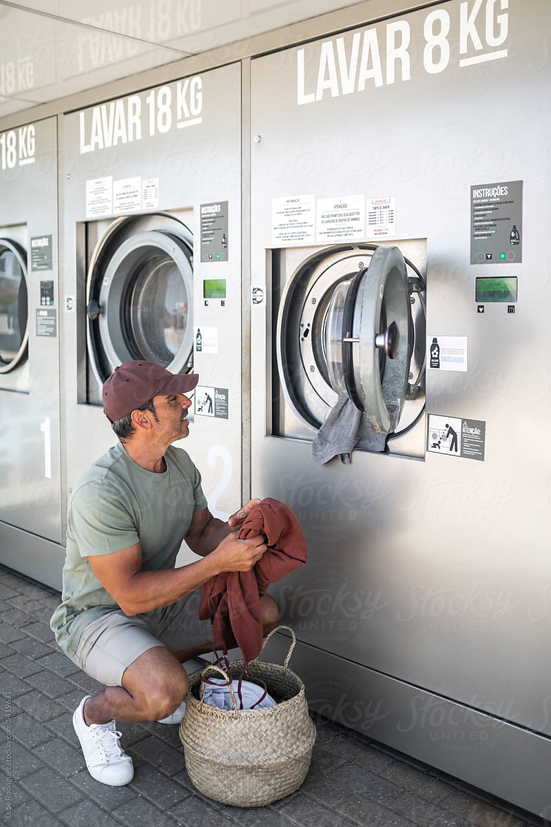 young man doing laundry in a city laundry
