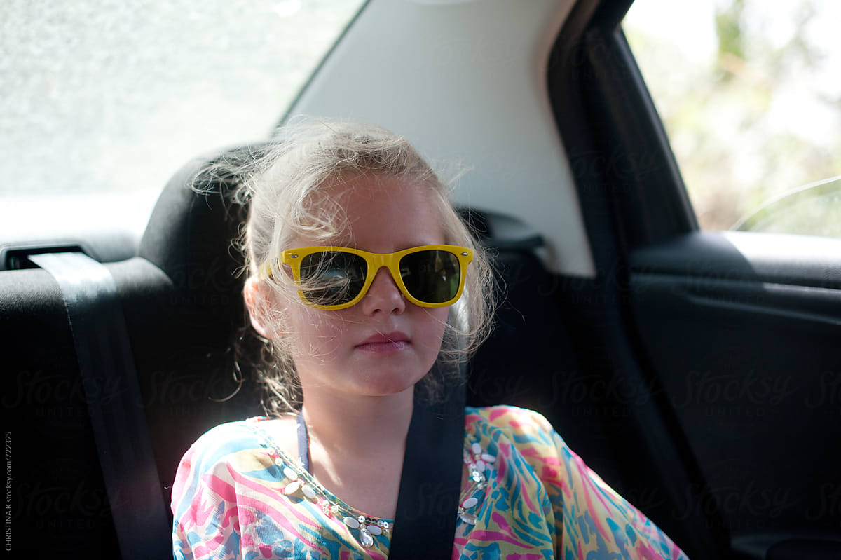 Girl in sunglasses sitting in the back of a car