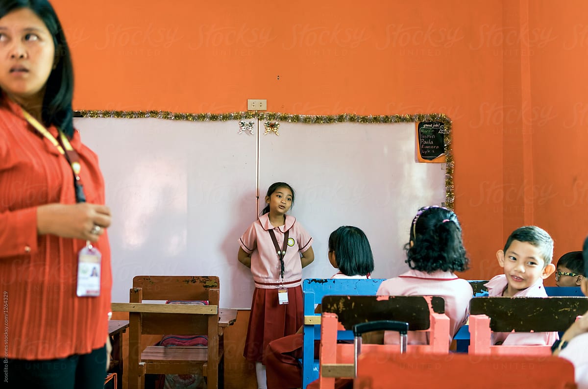 Young Female Student Recites in front of Class in School