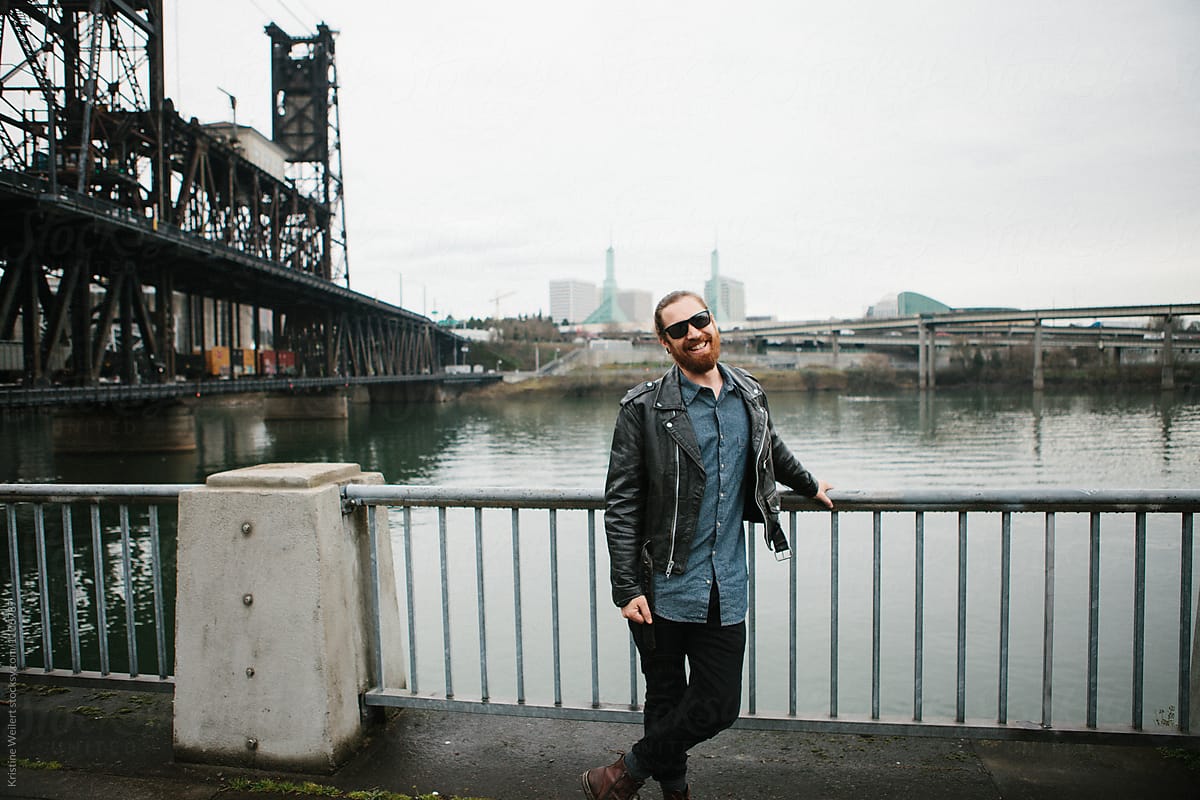 Hip man smiling with bridge and cityscape behind him