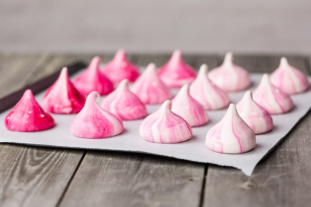 Pink meringue kisses on baking sheet